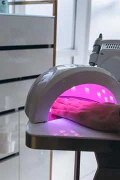 Manicure process. Drying nails in a device with ultraviolet lamps. Stock Photos