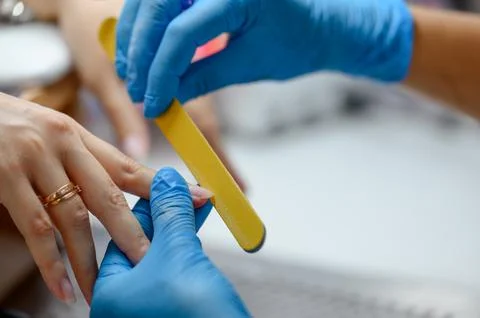 Manicure process with nail file and gloved hands in beauty salon Stock Photos