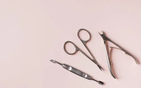 Manicure tools set of clipper scissors and cuticle pusher on light pink surface Foto stock