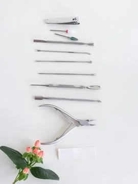 Manicure tools on white surface, top view, green plant. Beauty salon, aesthetics Stock Photos