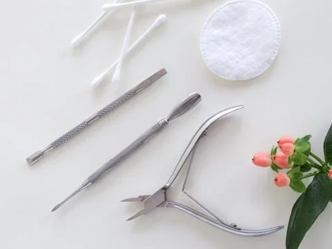 Manicure tools on white surface, top view, green plant. Beauty salon, aesthetics Stock Photos