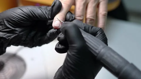 Manicures master in black gloves working with special drill cleaning nail Stock Footage 158084153