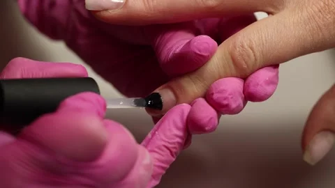 Manicurist applying base coat during nail treatment Stock Footage 308516529