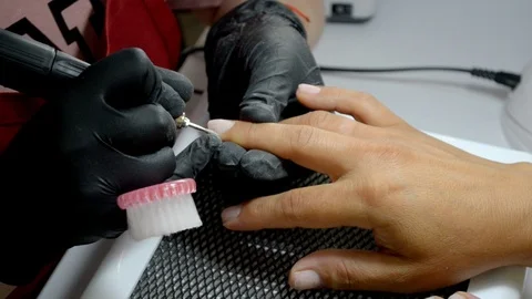 Manicurist in black gloves does hardware manicure, cleans finger of cuticle Stock Footage 122645414