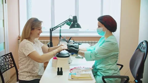The manicurist communicates with the client offering to make Stock Footage 152986597
