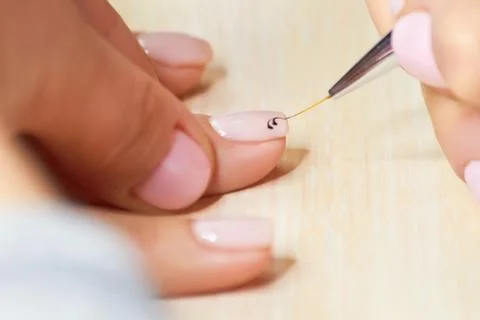 Manicurist drawing pattern on nails. Stockfoto's