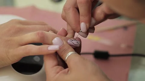 Manicurist draws a pattern on the nail of the ring finger. Stock Footage 231326198