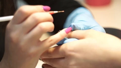 Manicurist draws a pink pattern on a black nail Video stock 126171319