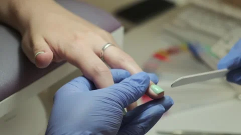 Manicurist files shape of nails. Nail art master shapes the nails with a nail Stock Footage 246927352