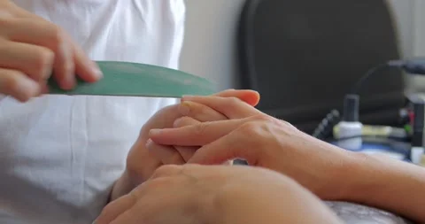 Manicurist files the shape of the nails with a special nail file, close up view Stock Footage 202685111