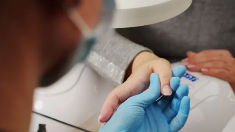 Manicurist files the shape of the nails with a special nail file, close up .. Stock Footage 265581180