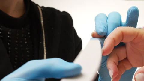 Manicurist files the shape of the nails with a special nail file, close up view. Stock Footage 303047481