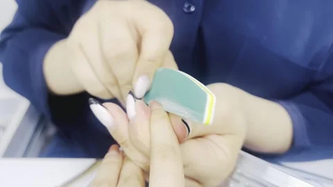 Manicurist filing nails with a buffer block Stock Footage 345145244