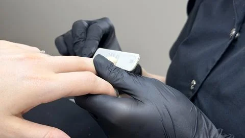 Manicurist filing nails of client Stock-Fotos