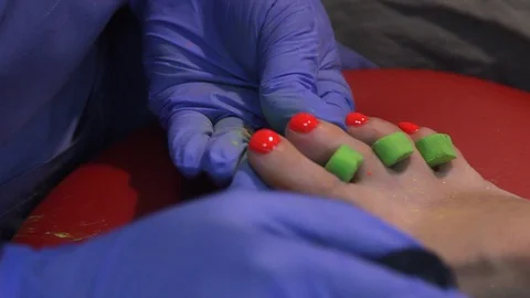 A manicurist gently puts a colored drawing on the toenails of a woman. doing man 動画素材 119227128