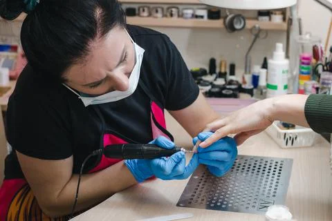 The manicurist makes the processing of the client's cuticle by hardware Stock Photos