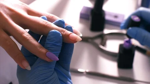 Manicurist master puts a violet shellac on client's nails. Stock Footage 110564593