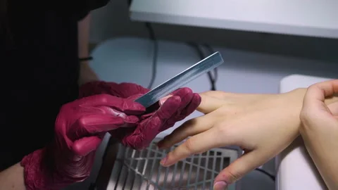 Manicurist with nail file adjusts shape of client nails by sawing them on sides Stock Footage 146488809
