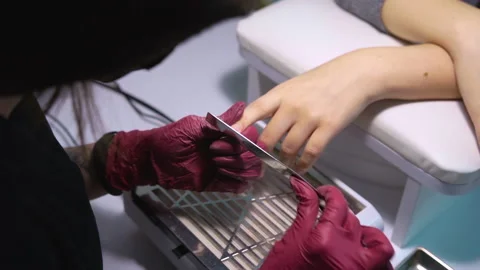 Manicurist with nail file adjusts shape of client's nails makes a square shape Stock Footage 146488887