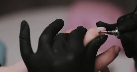 The manicurist processes the client's cuticle with a hardware machine.  Video stock 149366632