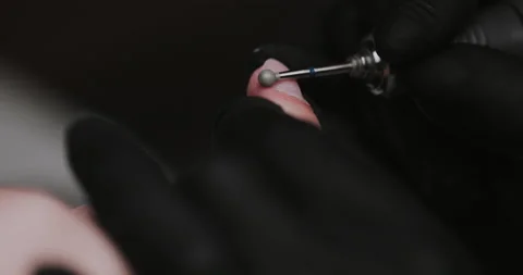 The manicurist processes the client's cuticle with a hardware machine.  Stock Footage 149366727