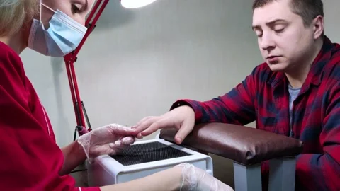 The manicurist processes the man's nails with a file. Professional care in a bea Stock Footage 144728514