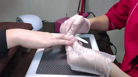 The manicurist processes the woman's nails with a file. Professional care in a b Stock Footage 144728241