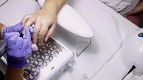 A manicurist treating a woman's cuticles using a manicure machine Stock Footage 256498443