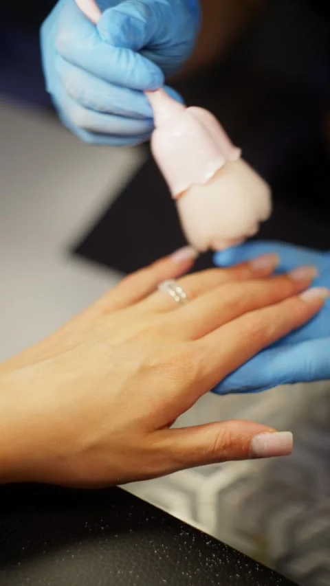 A manicurist uses a brush to remove dust from a client's hands. 스톡 동영상 343529435