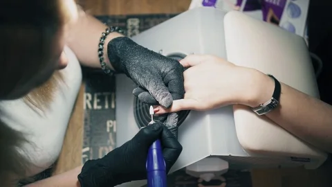 Manicurist is using nail tools to remove nail polish in nail salon view from Stock Footage 94030445