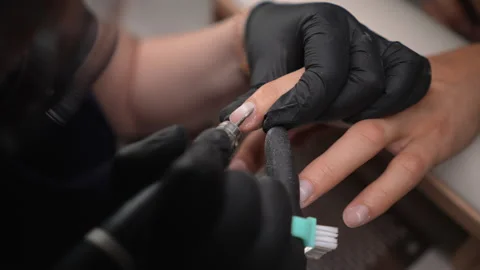Manicurist wearing black gloves using electric nail drill to grinding, polishing Stock Footage 287954262