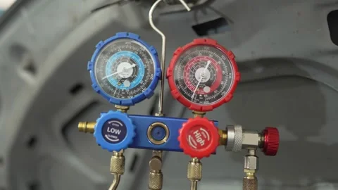 A manifold gauge hangs under an open car hood. Stock Footage 341335081
