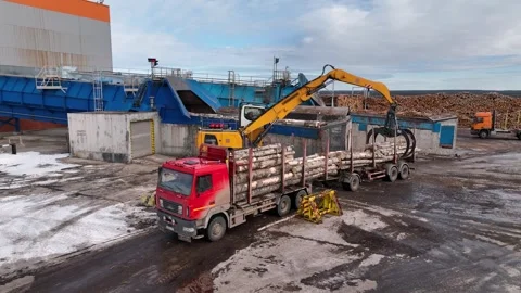 Manipulator crane unloads timber from a logging truck for processing Stockbeeldmateriaal 304648097