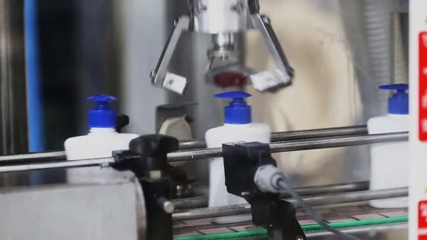 Manipulator robot twists caps of bottle on a conveyor belt Stock Footage 75779809
