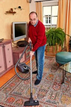  Mann bei Hausarbeit mit Staubsauger Mann reinigt die Wohnung - Hausarbeit... Stock Photos