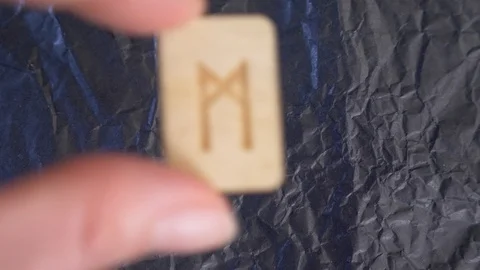 Mannaz rune. close-up, hand puts the rune on the surface for divination. 4k Stock Footage 87880112