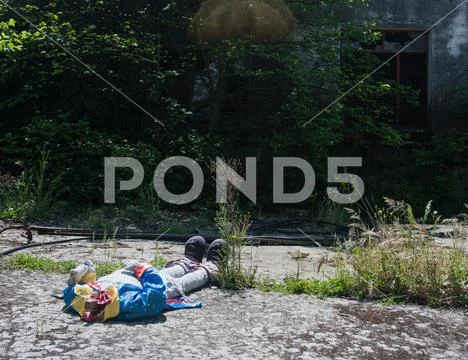Mannequin of a headless clown abandoned at the entrance to an old, unused fac Stock Photos
