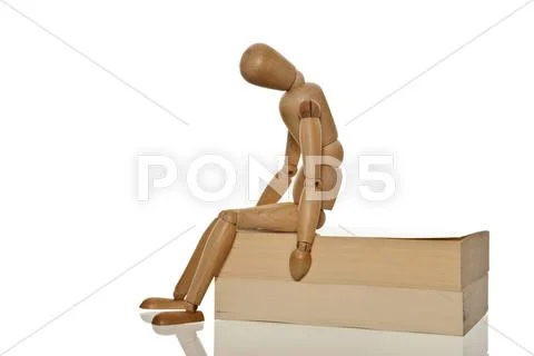 Mannequin looking desperate and exhausted while sitting on two books Stock Photos