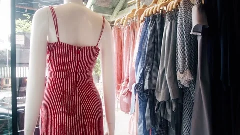 A mannequin in a red dress in a designer store next to the rack of clothes Stock Footage