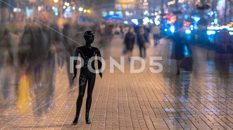 The mannequin standing on the evening street with people Stock Photos