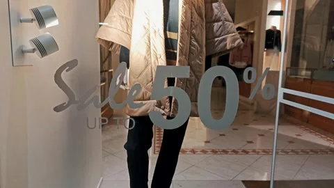 Mannequin wearing a stylish jacket behind a boutique glass showing a discount Stock-Footage 329259532