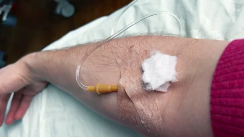 Man's arm with an IV needle in a vein. Intravenous injections, medical care Stock Footage 258704522