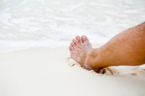 Man's bare foot on the beach. Stock Photos