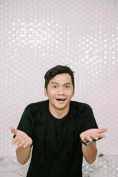 Man's bewildered expression with surprised gesture against hexagonal tiles Foto stock