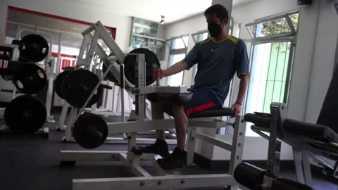A man's calves flexing exercising by lifting weights with his feet in the gym Video stock 164589172