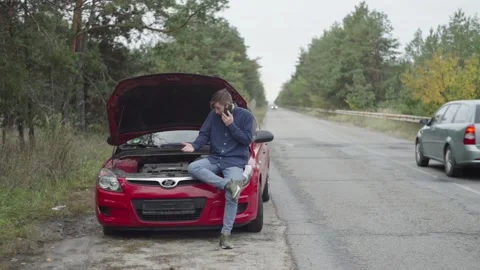 A man's car broke down and he calls for help. A guy with a phone near a car Stock Footage 221243824