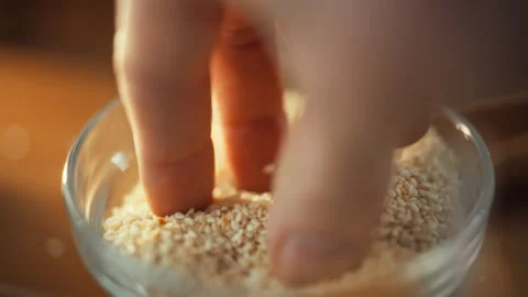 Mans cupped hands carefully inspect sesame grains as they fall pouring into Stock Footage 331355014