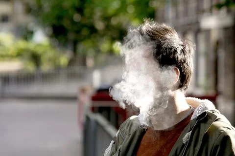 A man's face completely covered by thick cigarette smoke Foto stock