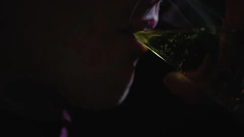 Man's face in the dark. A man drinks a yellow liquid from a glass. Stock Footage 236253960
