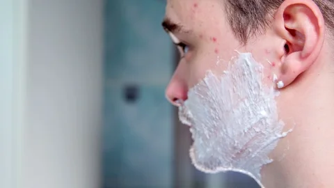 Man's face is full of foam and he starts to shave Stock Footage 87736908